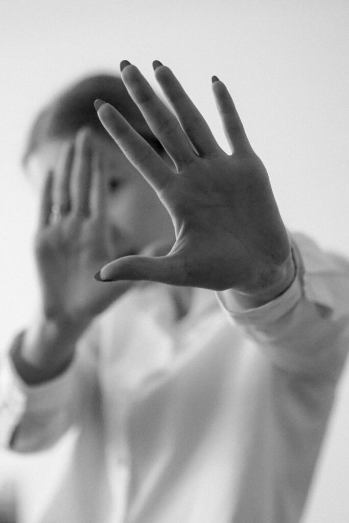 Black and white image of hands raised in a blocking gesture.