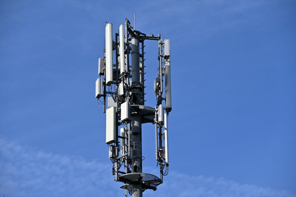 A modern cell tower with antennas against a clear blue sky, symbolizing connectivity.