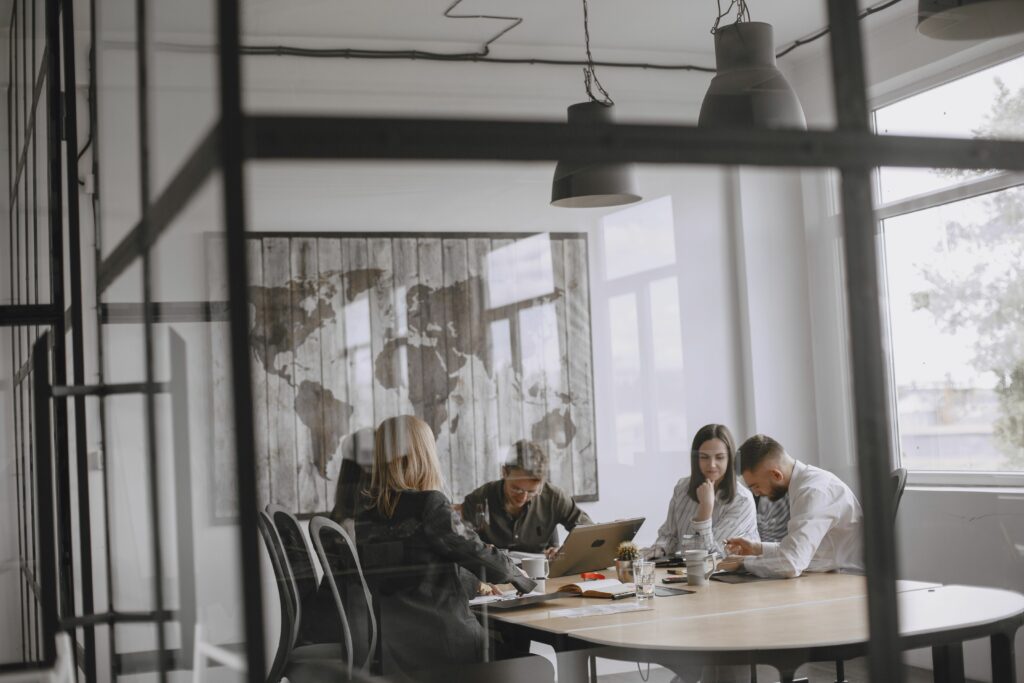 A group of professionals collaborate in a modern office with a world map decoration.